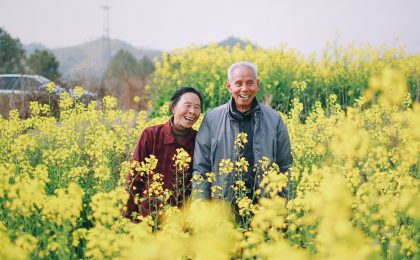 man and woman standing surrounded by yellow flowers