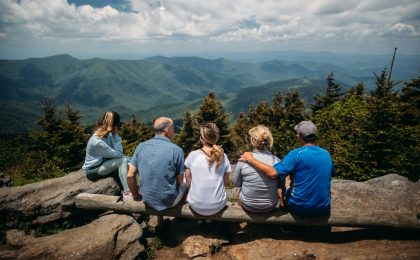 group of people sitting on rocks overlooking mountain